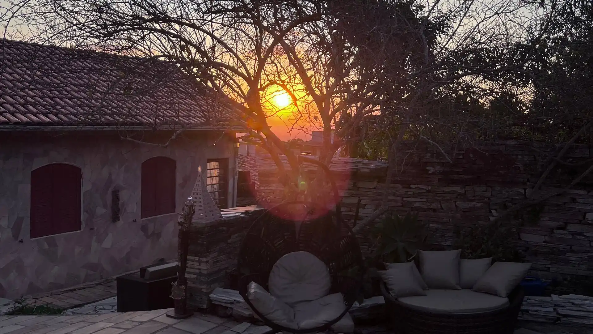 Pátio de pedra com o sol se pondo entre as árvores